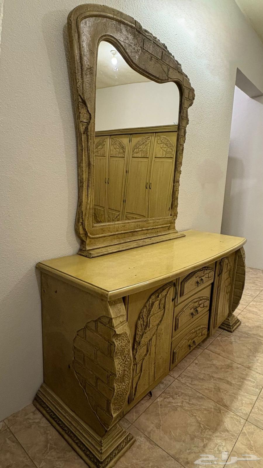 A wooden room with a large bed, wardrobe, and large dressing table and two nightstands63085591397378113