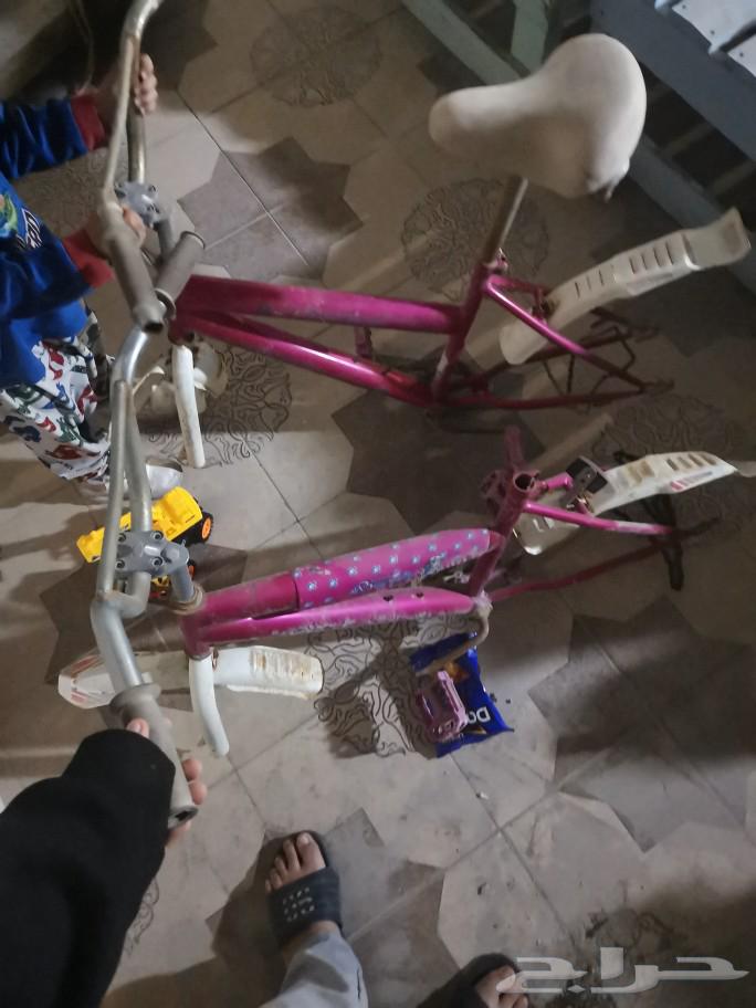 Two bikes with girls on them sharing one wheel and one tire.63533001894914116